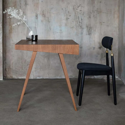 Wooden brown scandi retro desk with a black chair against a textured wall.