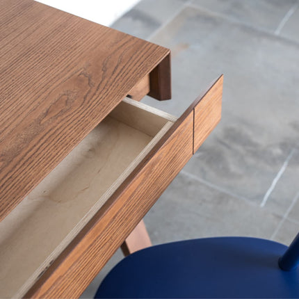 Brown stained Wooden desk with an open drawer, blurred background
