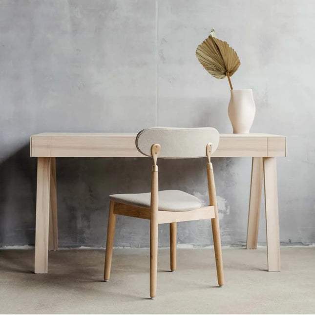 Modern wooden ash desk in a scandi design with chair against a concrete wall