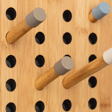 Wooden clothes rack pegboard with wooden pegs and black holes on a wooden background