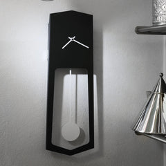 Modern black wall clock with pendulum design on a gray wall