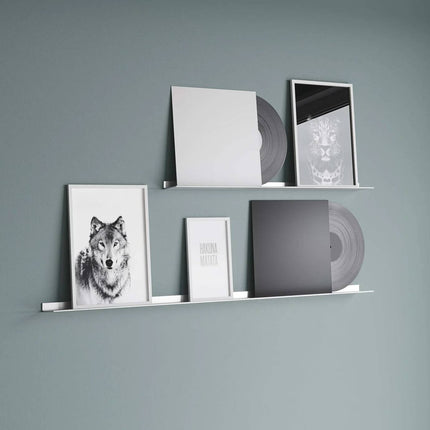 Metal frame shelves with vinyl records and framed pictures against a green wall