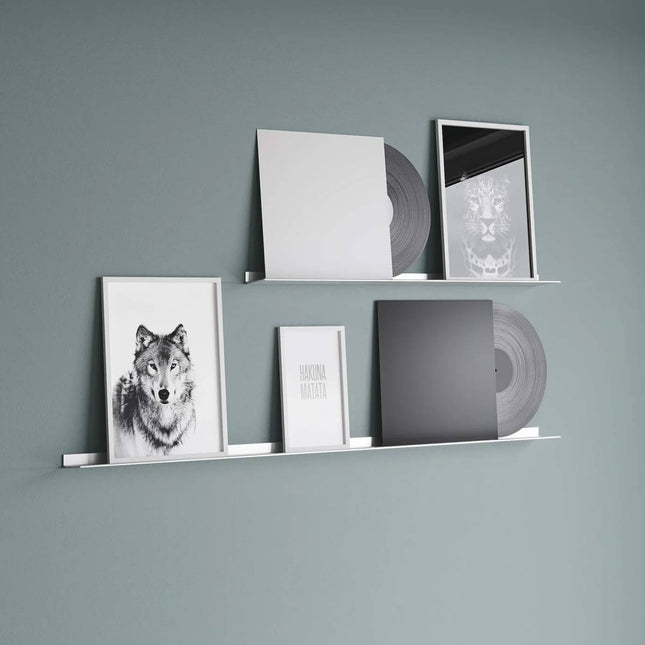 Metal frame shelves with vinyl records and framed pictures against a green wall