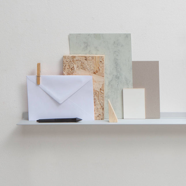 Set of stationery items including envelopes and cards on a light surface with a neutral background sitting on a metal frame shelf