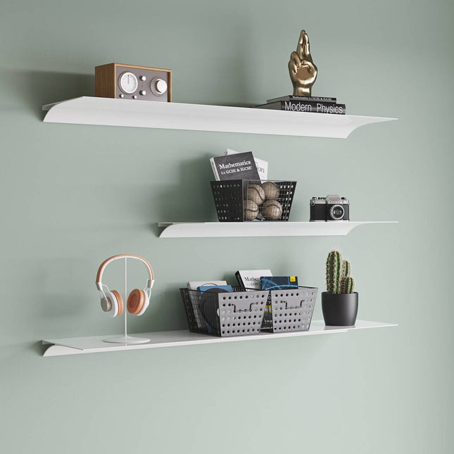 White metal shelves against a green wall with various items on them in a modern japandi style