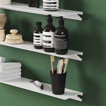 Modern Metal shelves with toiletries against a green wall