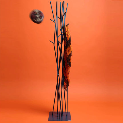Black metal coat rack with branches-like design against an orange background