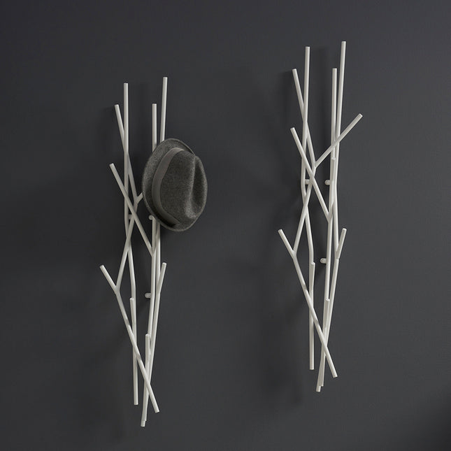 Wall-mounted metal branch-like coat rack with a hat on a dark background