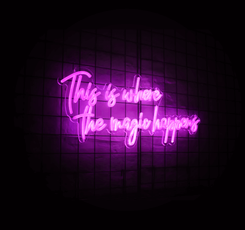 pink neon text light that says This is Where The Magic Happens