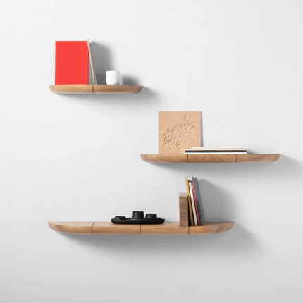 Set of three solid oak wooden shelves with various items on a white wall