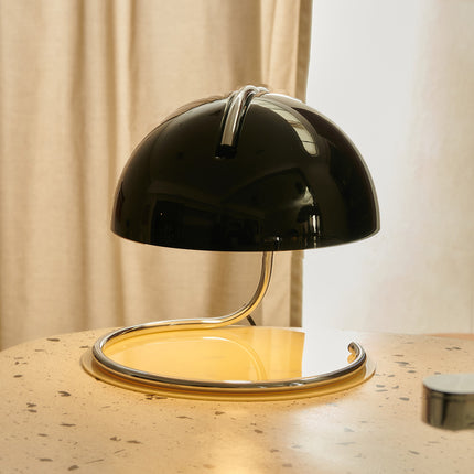 1970s style Black dome table lamp on a wooden surface with a neutral background
