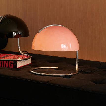 Retro Pink table lamp in 1970s style on a dark surface with a book underneath