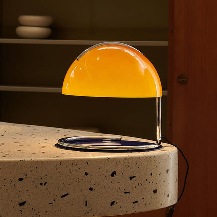 Yellow glass table lamp on a speckled surface with a blurred background