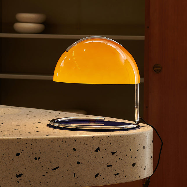 Yellow glass table lamp on a speckled surface with a blurred background