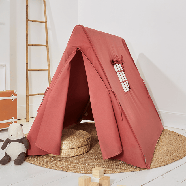 pastel red children's play tent with a ladder and toys on a light wooden floor sitting on a play mat