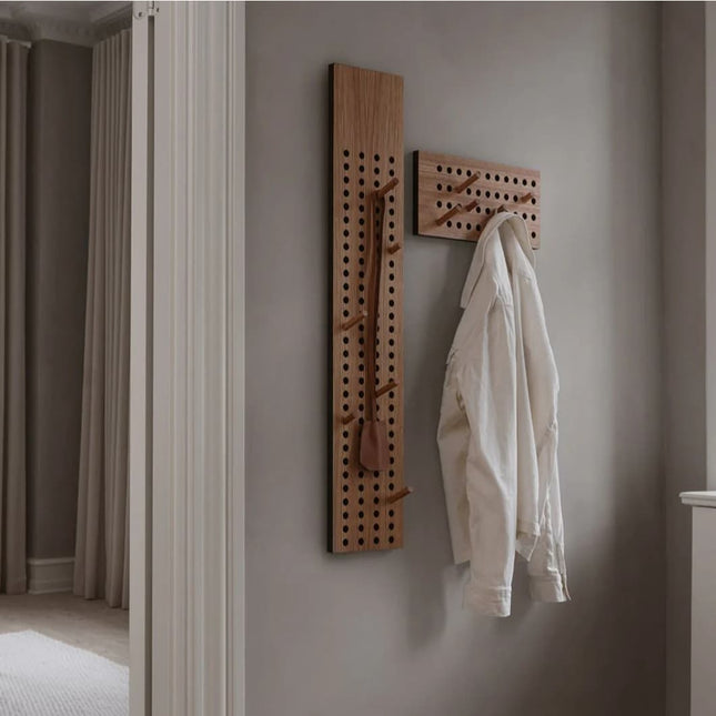 Wooden scoreboard clothes hooks on a wall with a white shirt hanging on it.