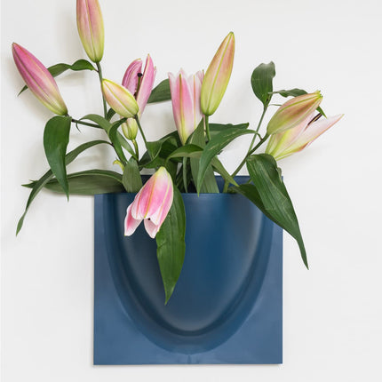 Pink and green lilies in a blue wall-mounted vertiplants planter on a white background