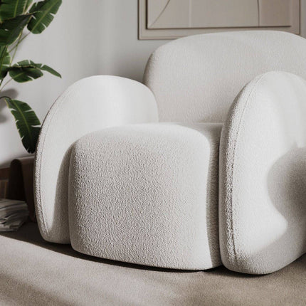 Modern white armchair in a room with a plant and neutral decor