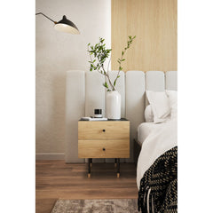 Wooden nightstand with a vase and plant next to a bed in a bedroom setting.