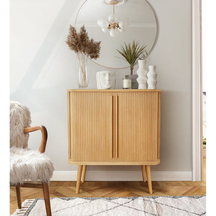 Wooden tambour highboard with decorative items in a room with a chair and mirror.